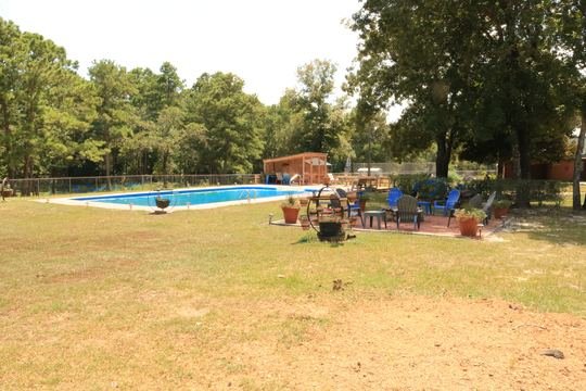 In-ground pool with blue water, pergola, and pink deck