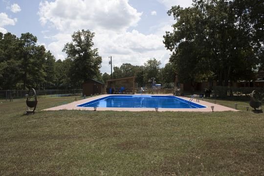 In-ground pool with blue water, pink deck, and yard lanterns