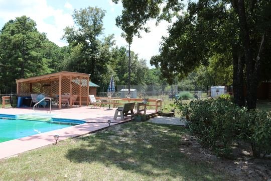 Pool deck, pergola, and lawn toward the log home